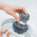 Soap-dispensing metal pot scrubber cleaning a cookware lid